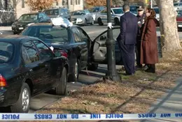 Detectives investigate a car at the scene of the shooting 